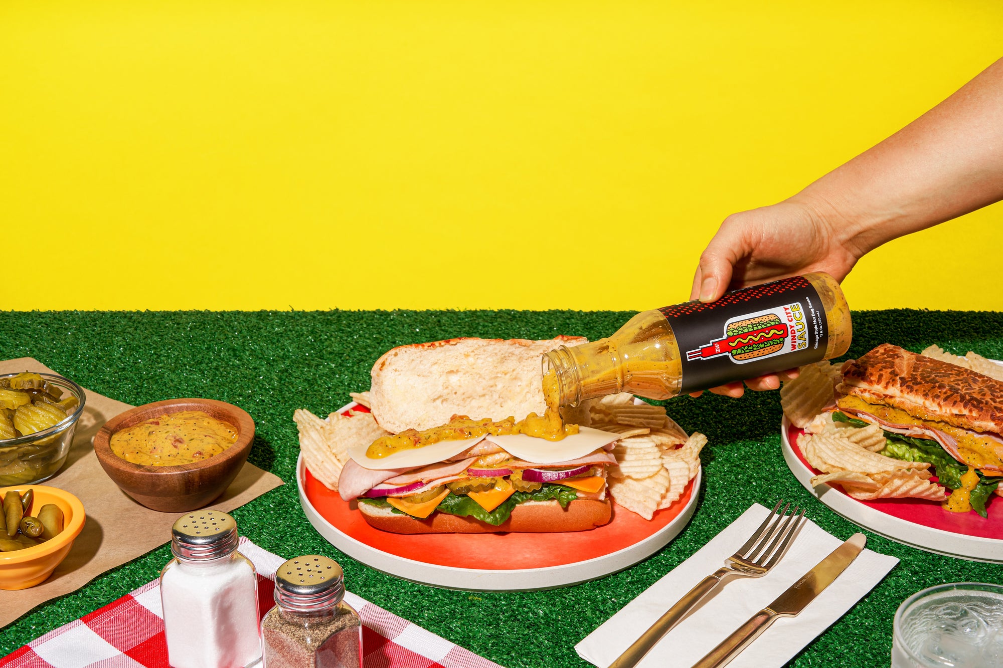 A bottle of mustard being held next to a hamburger